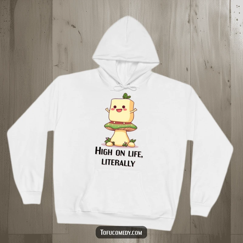 Funny hoodie showcasing a grinning anthropomorphic tofu slice balancing on a giant mushroom, offering comfort and humor.